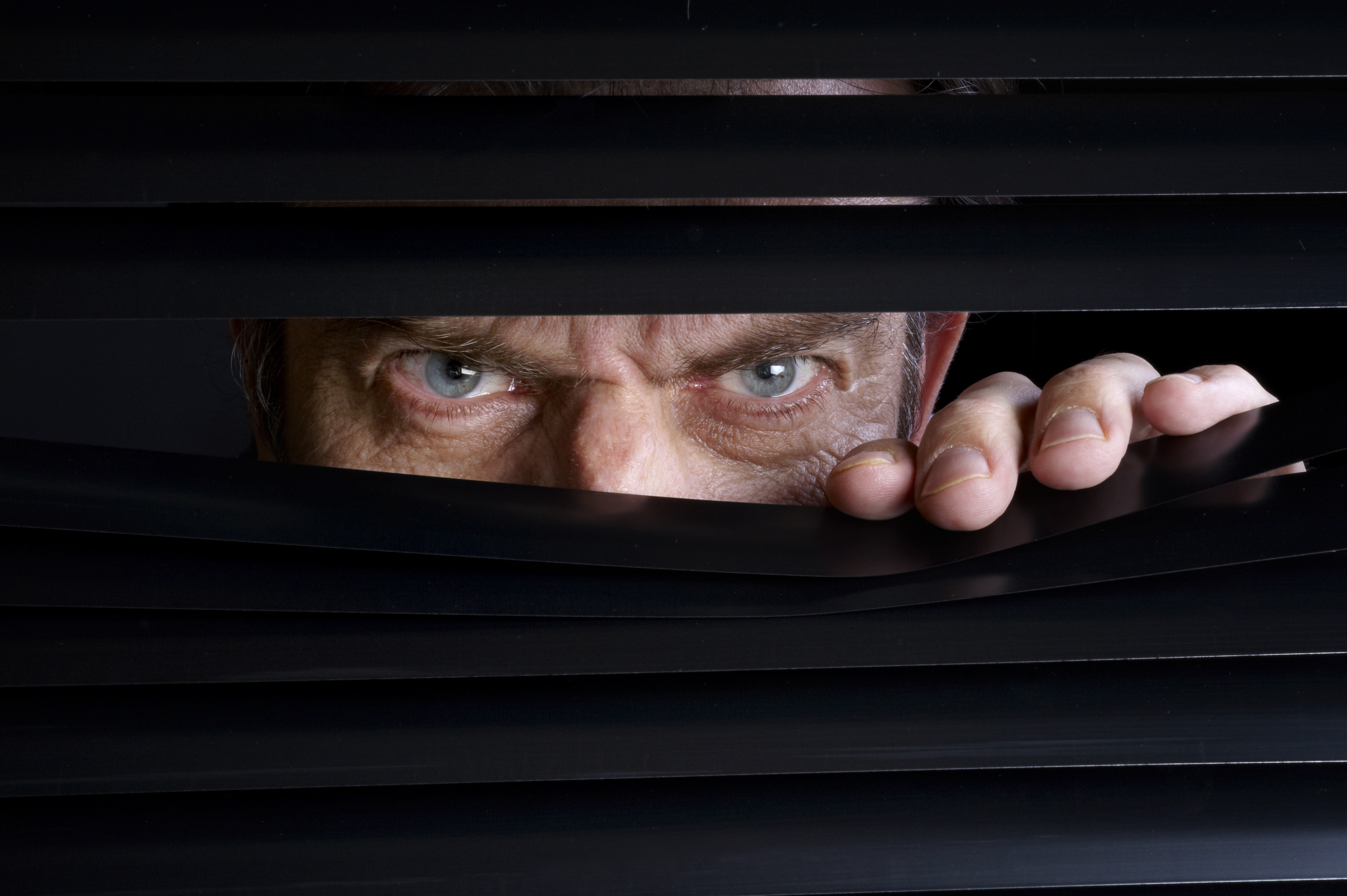 Man spying on something through venetian blinds